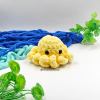 Handmade yellow crochet amigurumi octopus plush toy with cute black eyes, displayed with ocean-inspired background